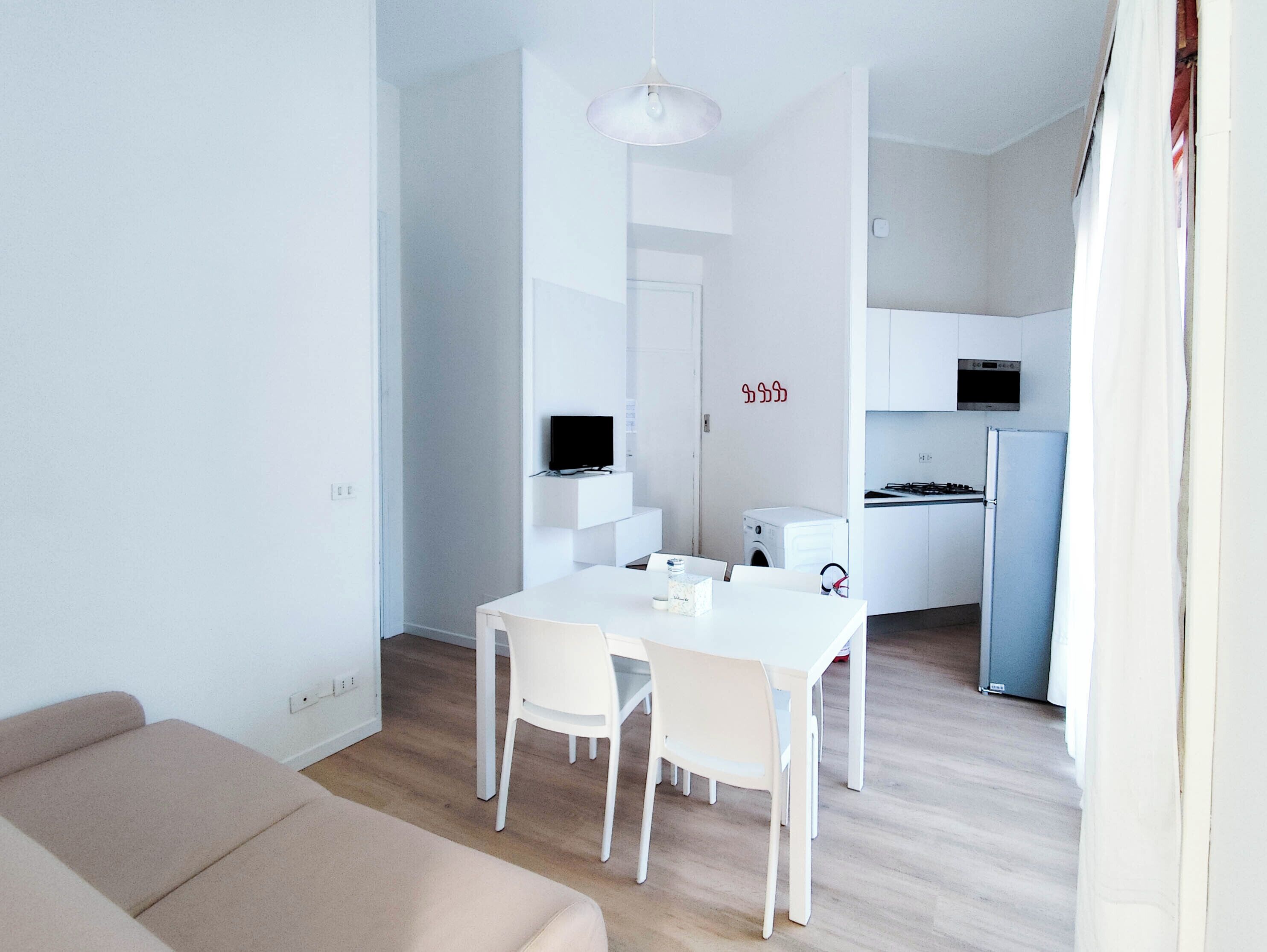 Um espaço de estar moderno e minimalista, com área de jantar, cozinha compacta e sofá.