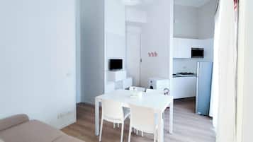 Um espaço de estar moderno e minimalista, com área de jantar, cozinha compacta e sofá.
