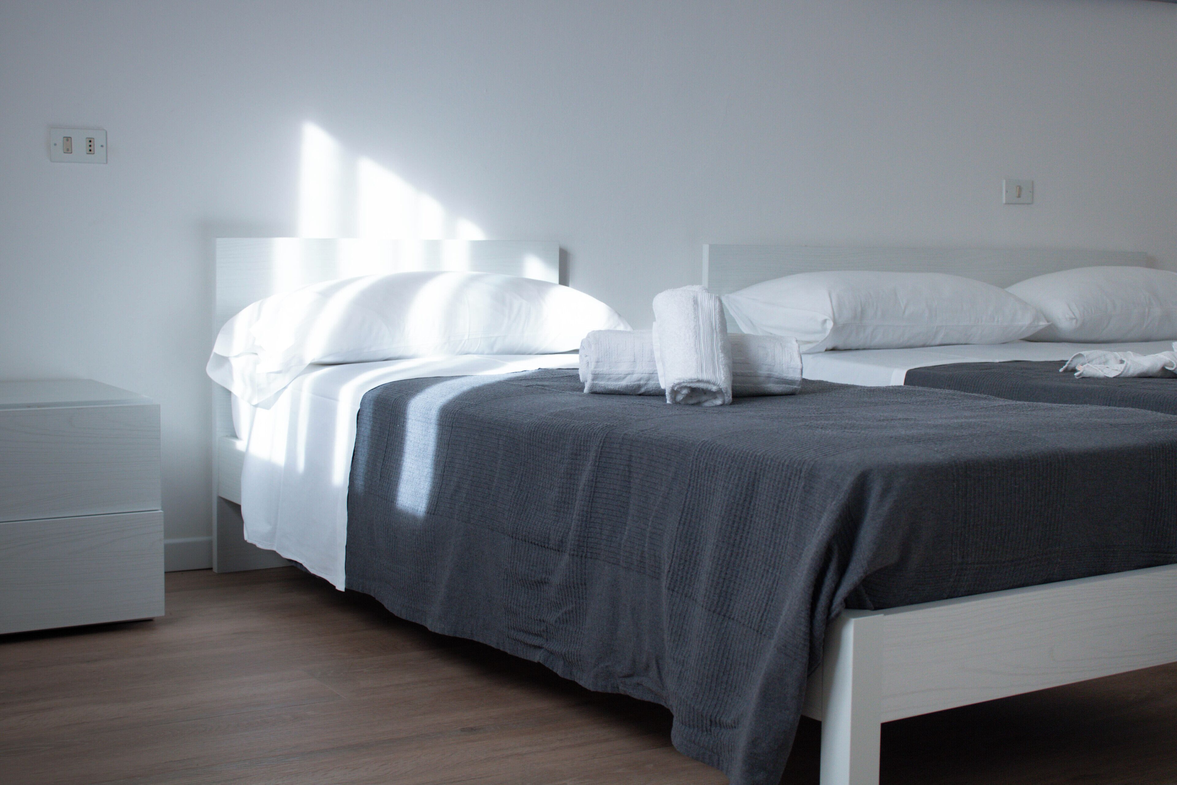 Quarto de hotel moderno com uma cama grande, mesa de cabeceira e armário.