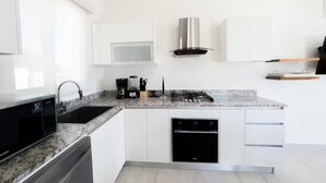Een moderne keuken met witte kasten, een ingebouwde magnetron, een gasfornuis en een vaatwasser.