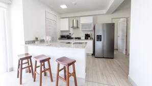 A modern kitchen with a central island, stainless steel appliances, and wooden stools.