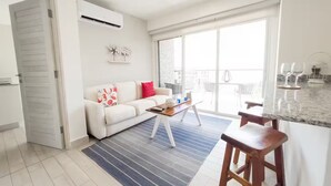A modern living room with a sofa, coffee table, and a view of the balcony.