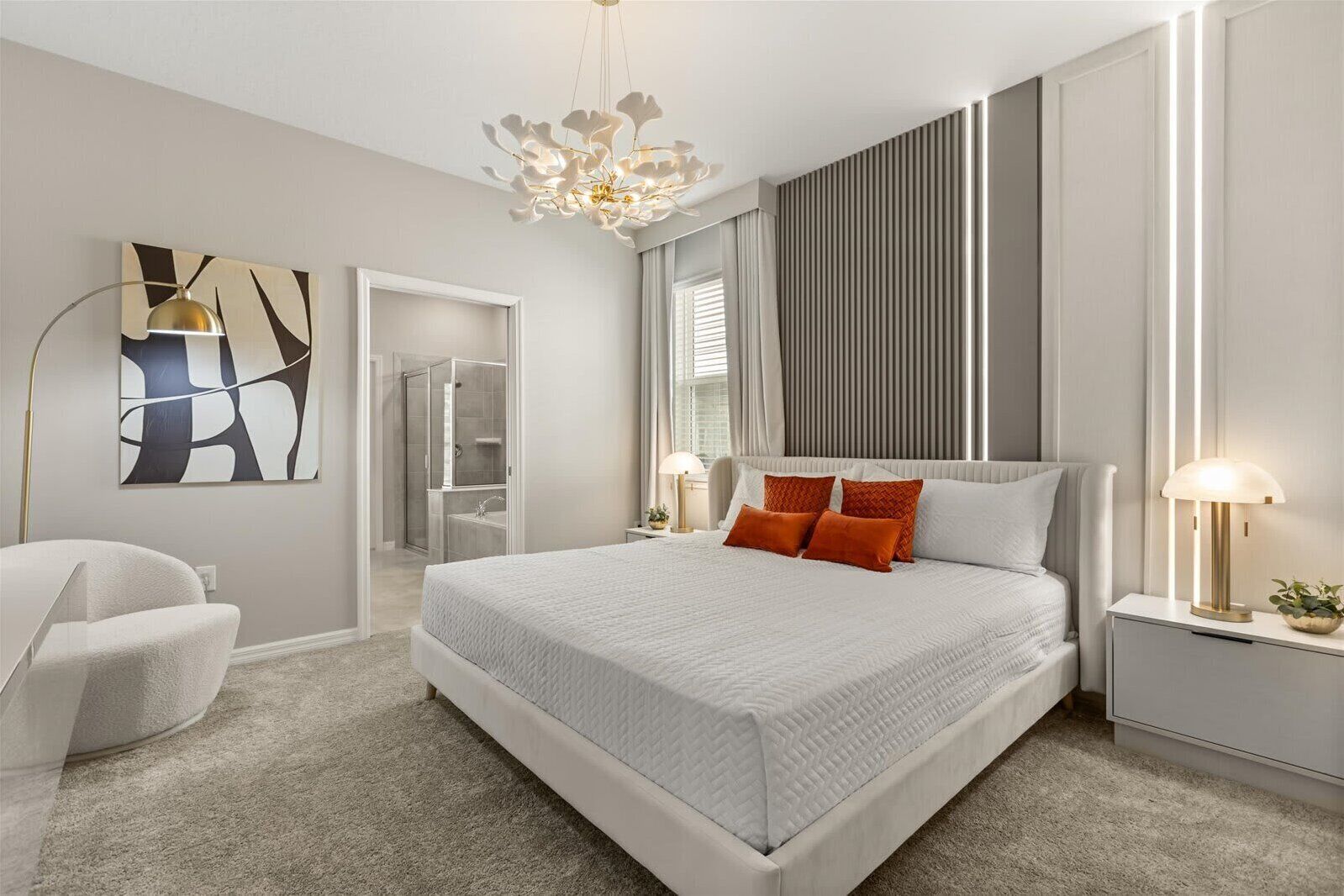 Un dormitorio moderno con una cama grande, vestidor, baño y una lámpara contemporánea.