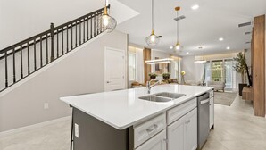 A modern kitchen with a central island, stainless steel appliances, and pendant lighting. - Mario | Minions | Theater | Private Pool | Disney 15883 (Clermont)
