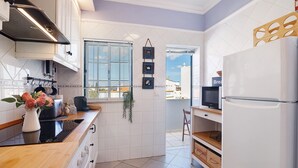 A modern kitchen with white cabinetry, a built-in oven, and a refrigerator. - Ria's Birds in Cabanas de Tavira – Comfort and Nature by the Ria Formosa (Cabanas de Tavira)