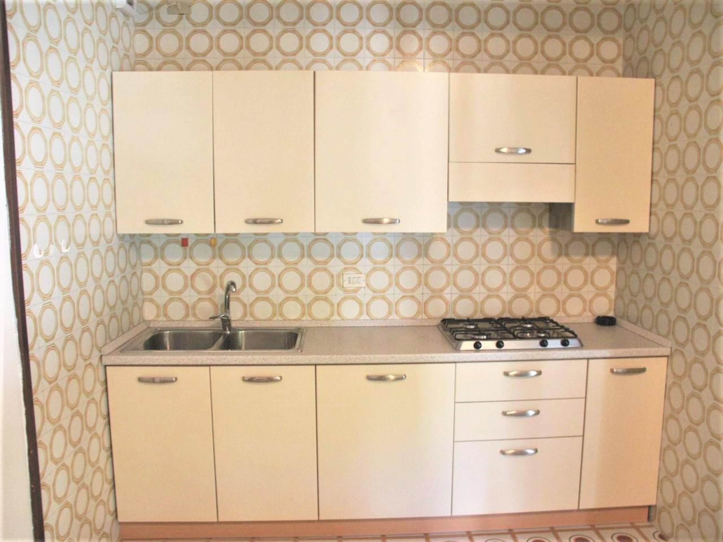 Uma cozinha com pia, fogão e armários.