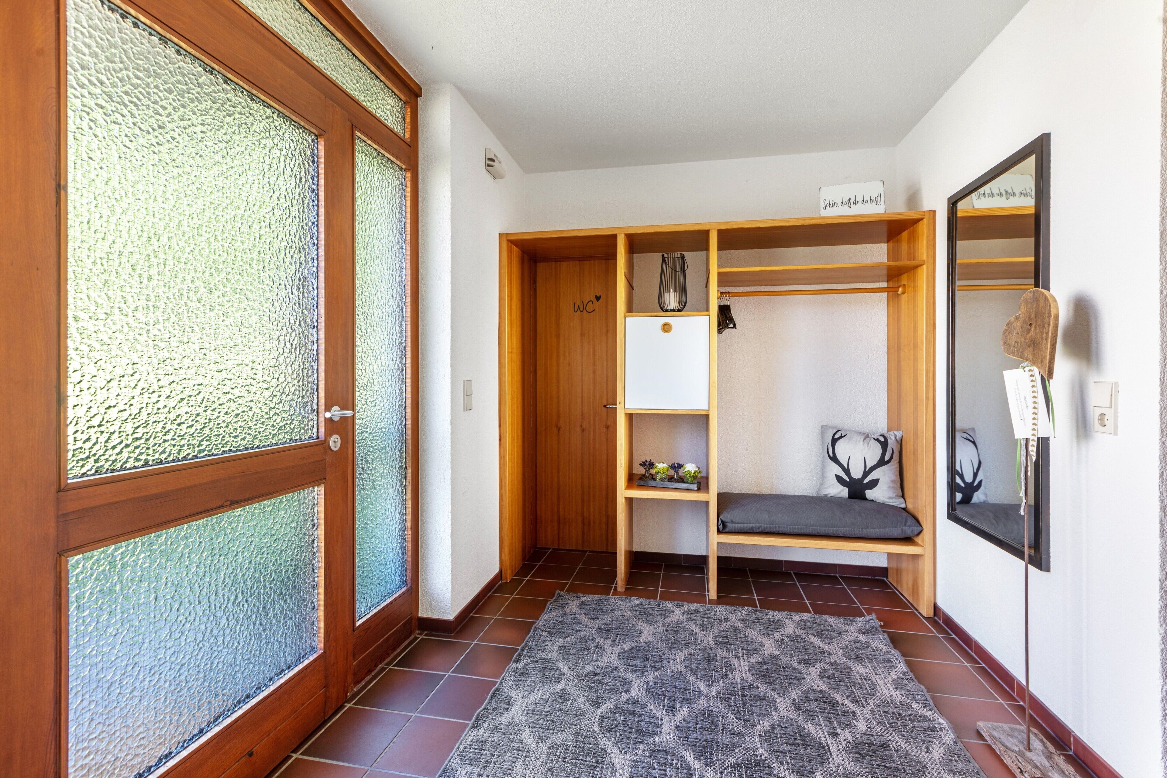 Une pièce comprenant une armoire en bois, un banc, un miroir et une petite étagère sur laquelle est posée une plante.