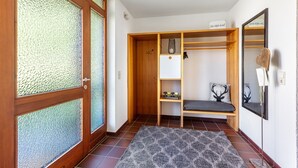 Um quarto com um guarda-roupa de madeira, um banco, um espelho e uma pequena estante com uma planta.