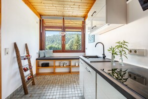 A compact kitchen with a window view, wooden shelves, and a built-in bench. - Haus Galerie – Unique Three-Story Vacation Apartment by the Stream with Terrace, 2 Baths & Gallery (St. Blasien)