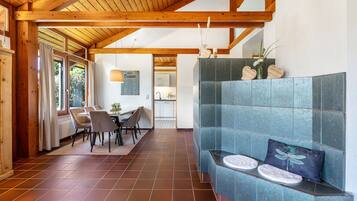 A modern interior with a dining area, a blue cushioned seating area, and a kitchen in the background.
