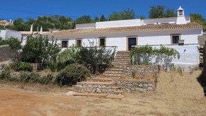 Un bâtiment blanc avec un toit en tuiles, des marches en pierre et un petit jardin.