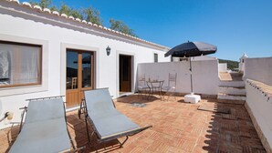 A rooftop patio with two lounge chairs, a table, and an umbrella. - Apartment 'Paz E Natureza 3' with Wi-Fi (São Brás de Alportel)