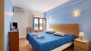 A bedroom with a bed, bedside table, nightstand, wardrobe, and an air conditioning unit. - Apartment 'Paz E Natureza 3' with Wi-Fi (São Brás de Alportel)