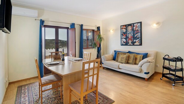 A dining area with a table, chairs, and a view through a window. - Apartment 'Paz E Natureza 3' with Wi-Fi (São Brás de Alportel)