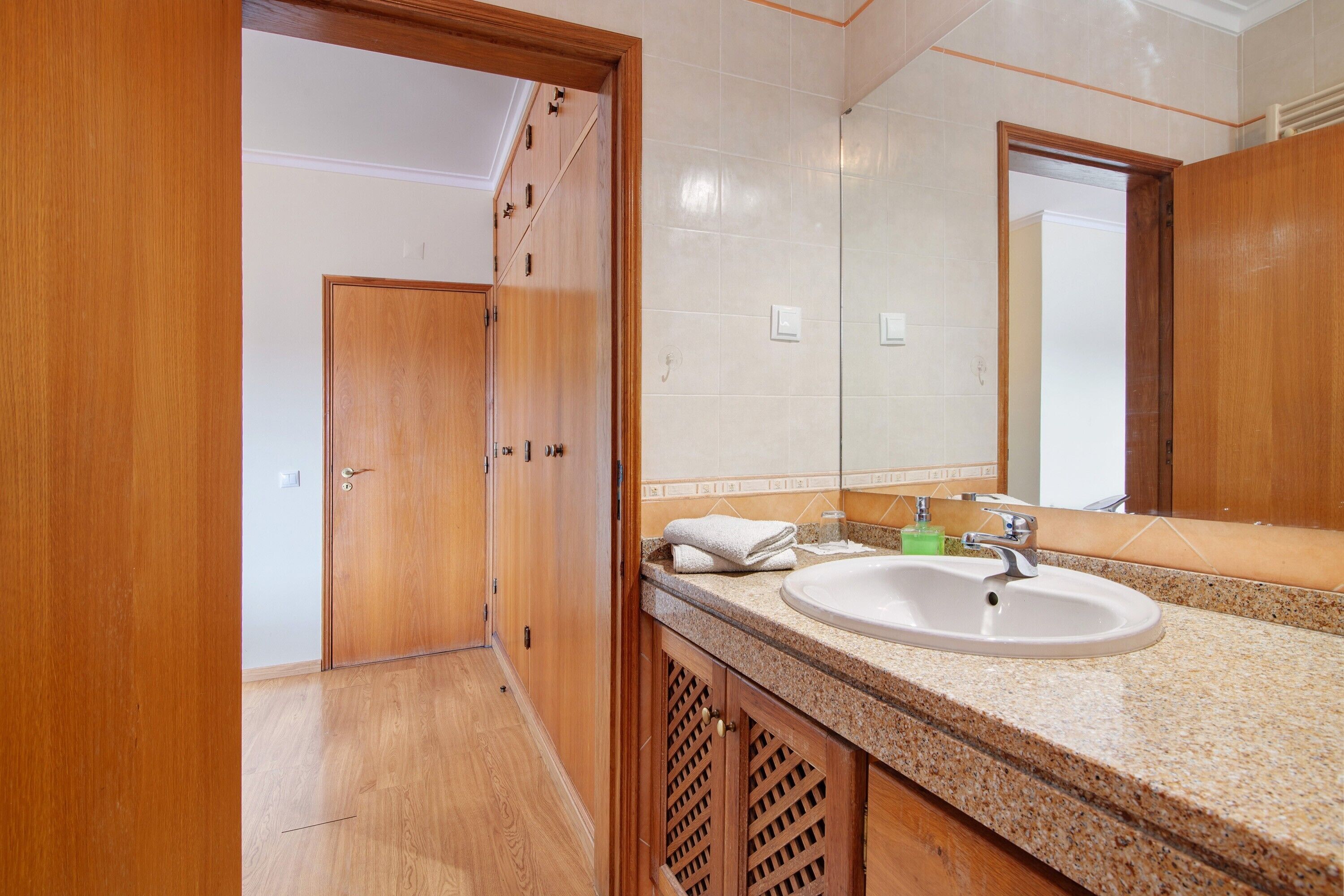 A bathroom with wooden cabinets, a granite countertop, a sink, and a mirror.