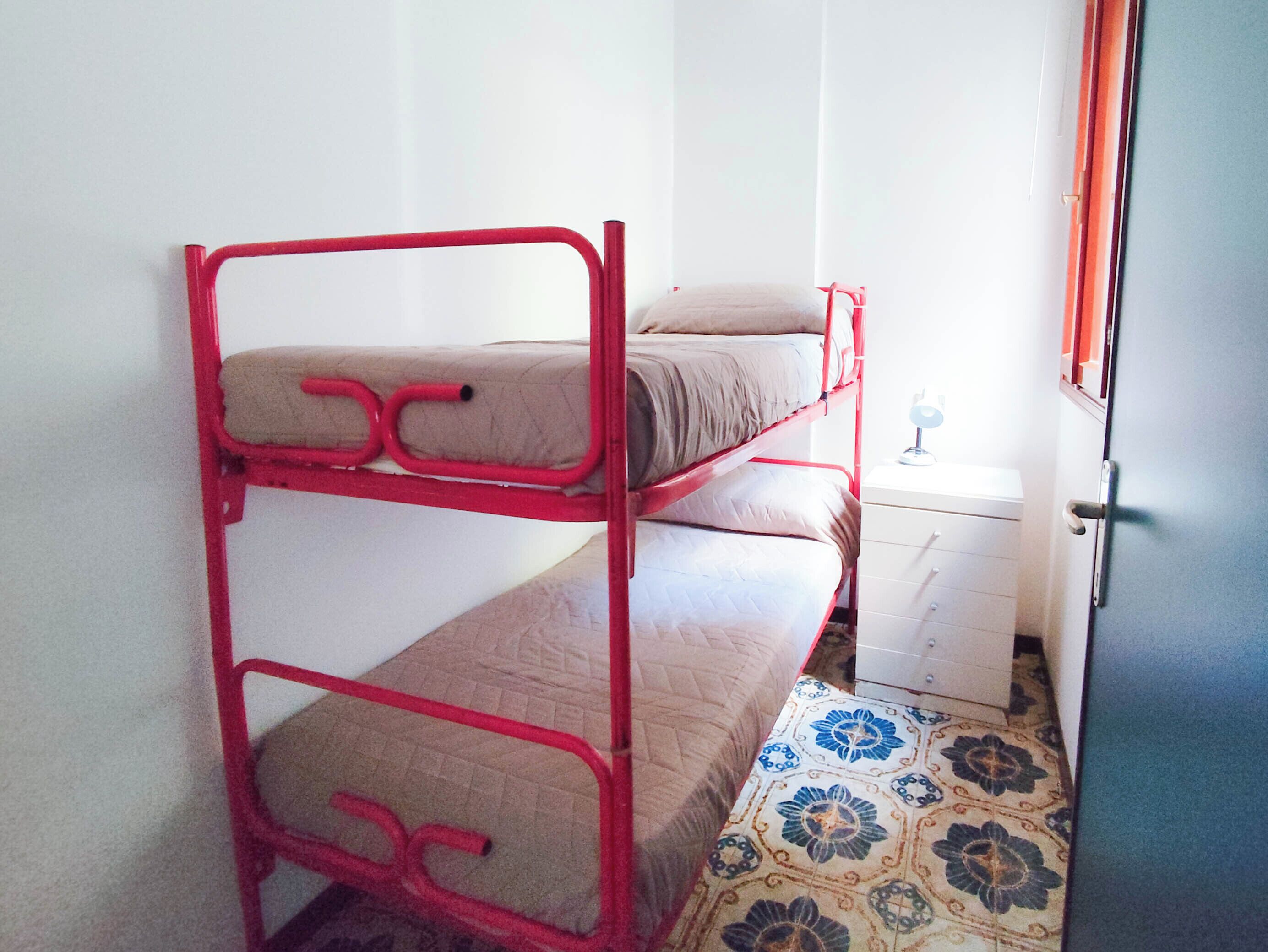 Un letto a castello con due letti, un comodino e un pavimento decorato.