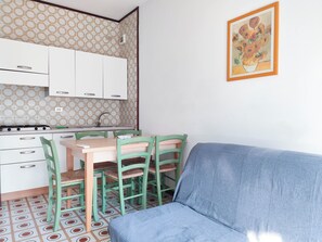 Una cocina compacta con comedor, que incluye un sofá, sillas y un cuadro en la pared.