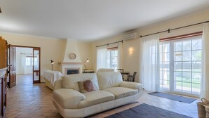 Un salón amplio con sofá, chimenea y ventanas grandes.