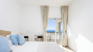 Habitación de hotel moderna con una cama grande, un escritorio y vista al mar.
