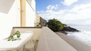 Un balcón con mesa y sillas, con vista a una playa y al océano.