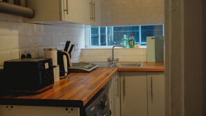A kitchen with white cabinets, a wooden countertop, a toaster, a sink, and a window with a view. - Modern Family Home in Rotherham, Long-Stay Friendly. (Parkgate)