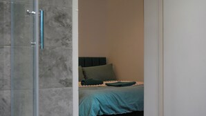 A bedroom with a bed, a headboard, and a shower area. - Modern Family Home in Rotherham, Long-Stay Friendly. (Parkgate)