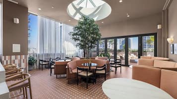 Un área de estar moderna con disposiciones de asientos, una mesa central y una planta grande en maceta.