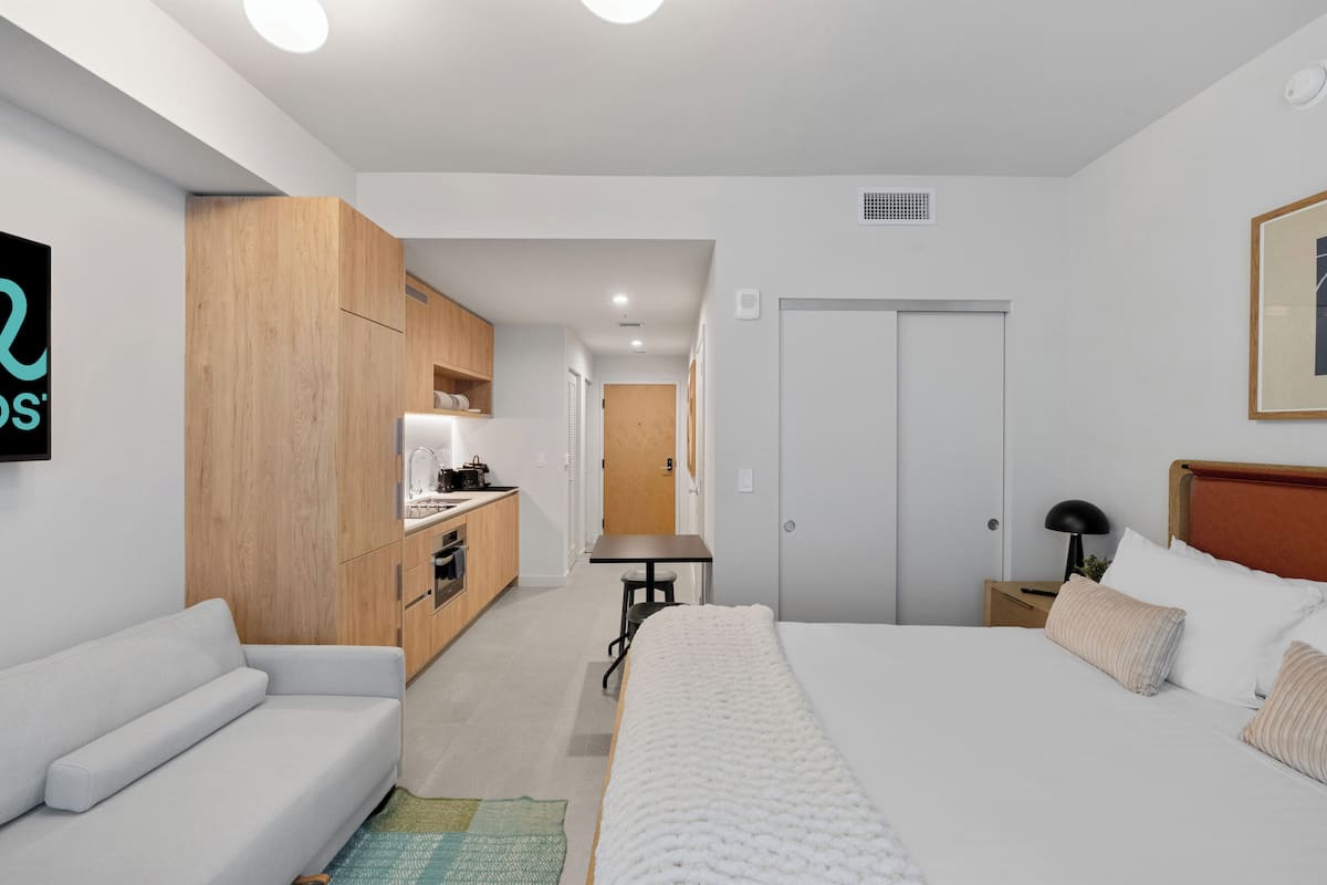 Une chambre d’hôtel moderne équipée d’un lit, d’un canapé, d’une kitchenette et d’une salle de bain.