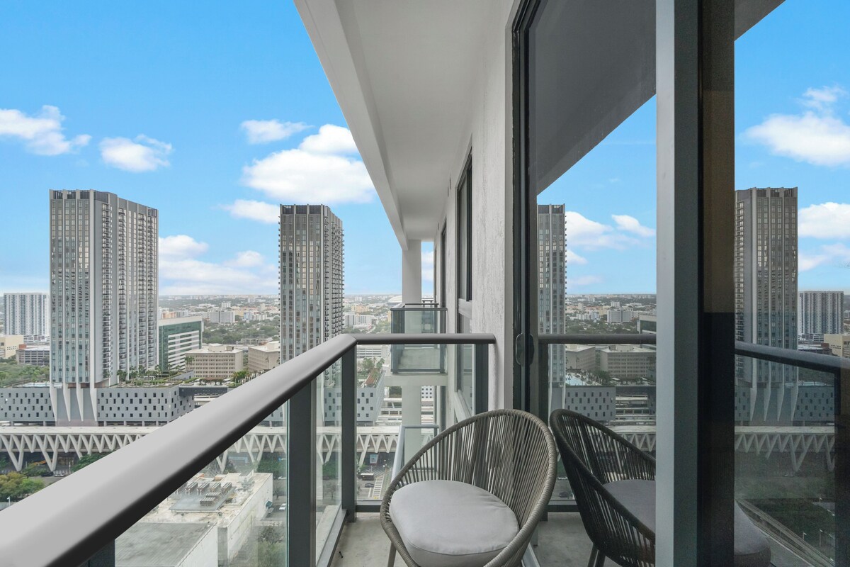 A balcony with a view of a cityscape, featuring high-rise buildings and a clear sky.