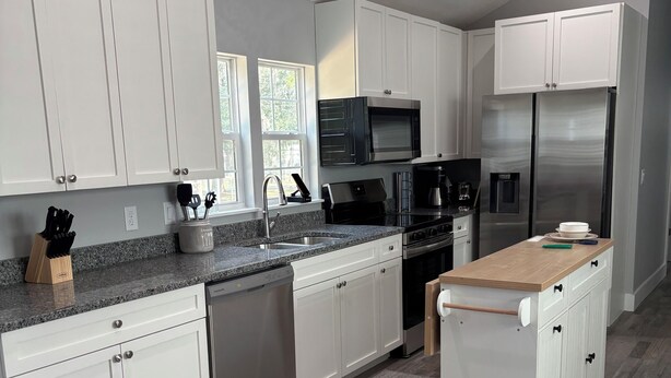 A modern kitchen with white cabinets, stainless steel appliances, and a granite countertop. - 3 blocks from boat dock see the festivals and bands from back porc (Homosassa)