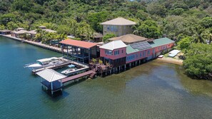 Une propriété située au bord de l’eau, dotée d’un quai, d’un bâtiment à toit rouge et d’une grande maison avec balcon.
