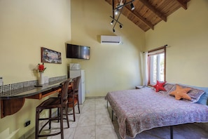 Une chambre comprenant un lit, un bureau avec des chaises, une télévision et un appareil de climatisation.