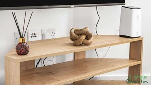 Ein Holztisch mit dekorativer Knoten-Mitte, eine Vase mit Schilfrohren und ein weißer Lautsprecher.
