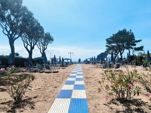 A beach path with blue and white tiles, surrounded by beach chairs and umbrellas, leading to the sea. - Cozy Studio Near the Beach (Jesolo)