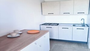 A kitchen with white cabinets, a wooden countertop, a gas stove, and a sink. - Cozy Studio Near the Beach (Jesolo)