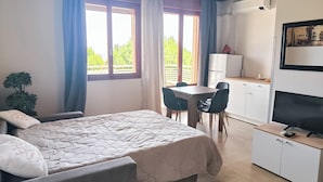 A bedroom with a bed, a desk, and a kitchenette. - Cozy Studio Near the Beach (Jesolo)
