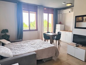 A bedroom with a bed, a desk, and a kitchenette. - Cozy Studio Near the Beach (Jesolo)