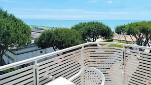 A balcony with a view of the sea, trees, and a beach area. - Cozy Studio Near the Beach (Jesolo)