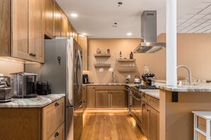 A modern kitchen with wooden cabinets, stainless steel appliances, and a marble countertop. - Timberframe Lodge| Hocking Hills, Luxury, Pond (Rockbridge)