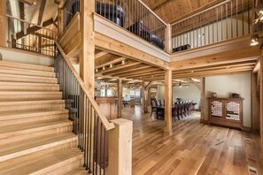 A spacious interior with a wooden staircase, a dining area, and a kitchen. - Timberframe Lodge| Hocking Hills, Luxury, Pond (Rockbridge)