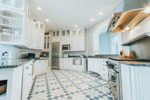 Une cuisine moderne avec des meubles blancs, un carrelage à motifs et des appareils électroménagers en acier inoxydable.