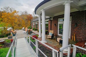 A covered patio area with outdoor seating and a brick exterior wall. - Hocking Manor | Hocking Hills, 8BR, Indoor Pool (Rockbridge)