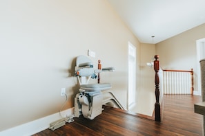 A room with a wooden floor, a white wall, and a wooden railing. - Hocking Manor | Hocking Hills, 8BR, Indoor Pool (Rockbridge)