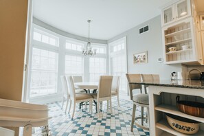 Une cuisine avec un carrelage à motifs, des meubles blancs et un lustre.