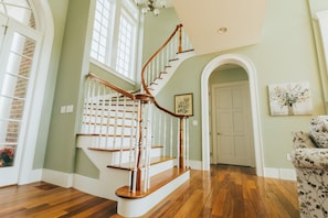 A staircase with wooden steps and white balusters, leading to a door. - Hocking Manor | Hocking Hills, 8BR, Indoor Pool (Rockbridge)