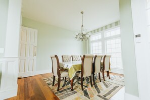 Une salle à manger avec une table en bois, six chaises et un lustre.