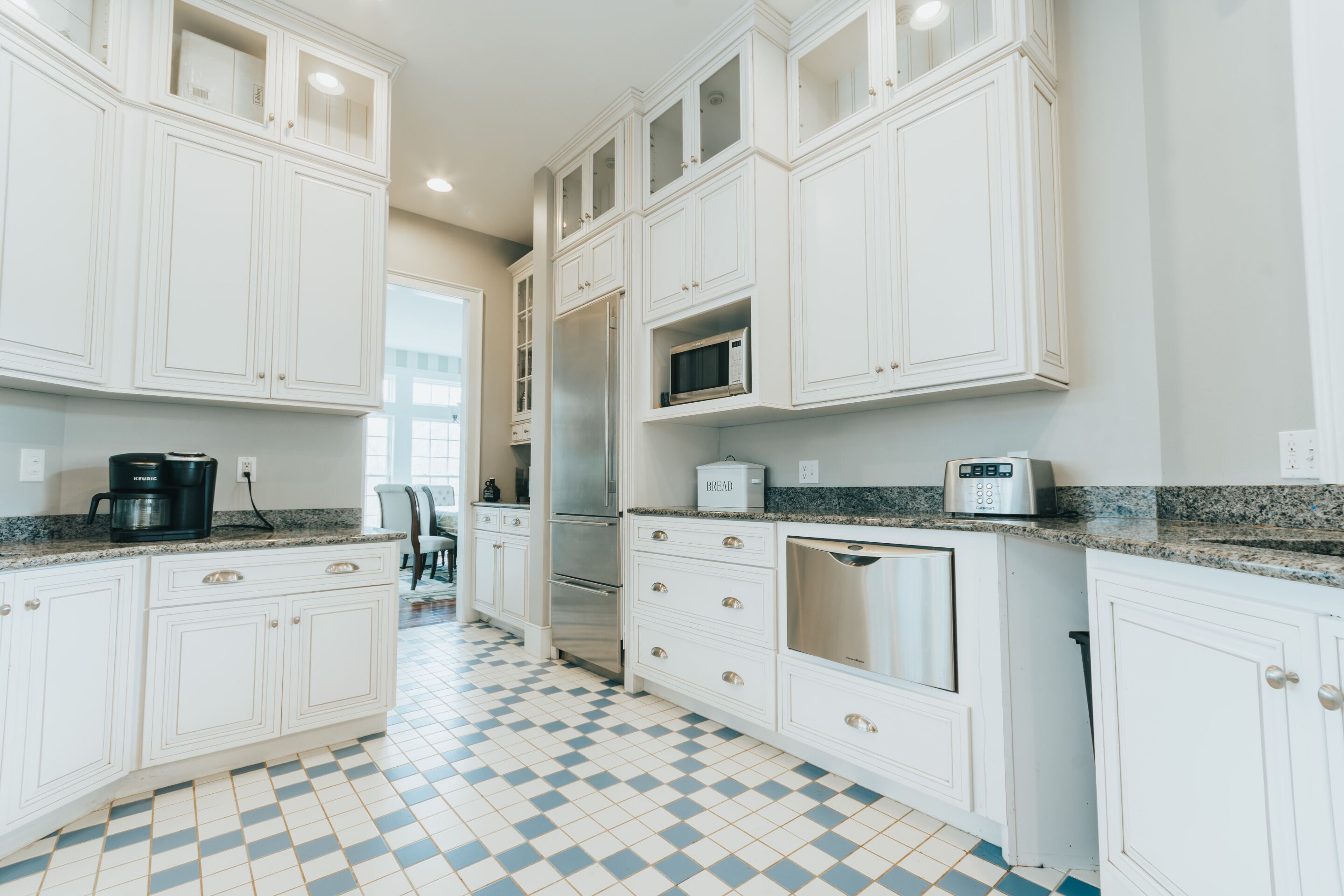 A kitchen with white cabinets, a microwave, and a coffee maker.