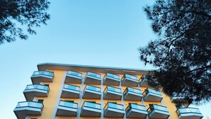 A multi-story building with a yellow facade and multiple balconies. - Relaxing Flat With Pool Access (Jesolo)