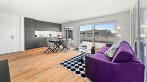 A modern apartment with a kitchen, dining area, and living room with a purple sofa. - Appartement B3 13 (Avenches)