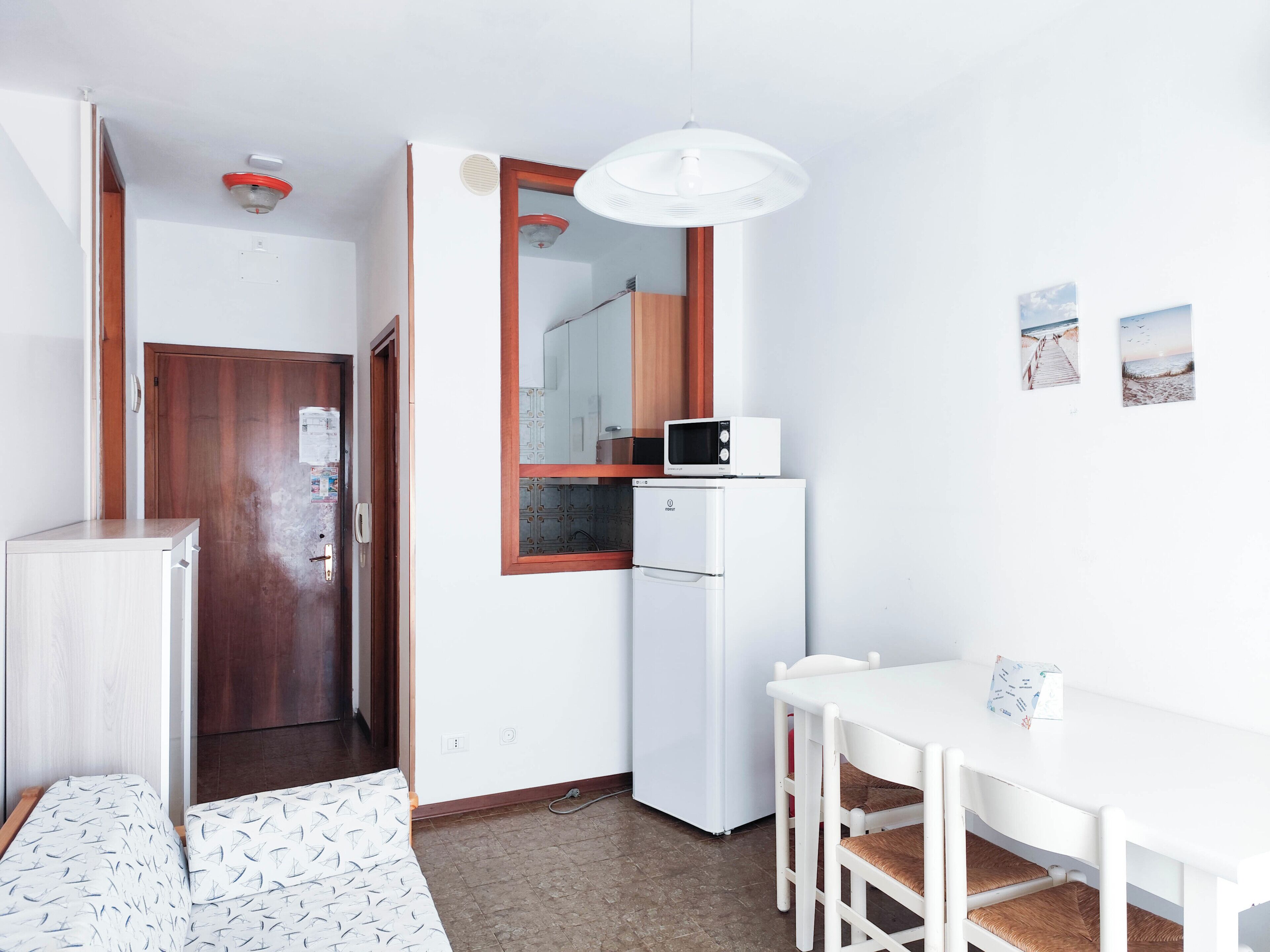A compact kitchen with a microwave, refrigerator, and a dining area with a table and chairs.